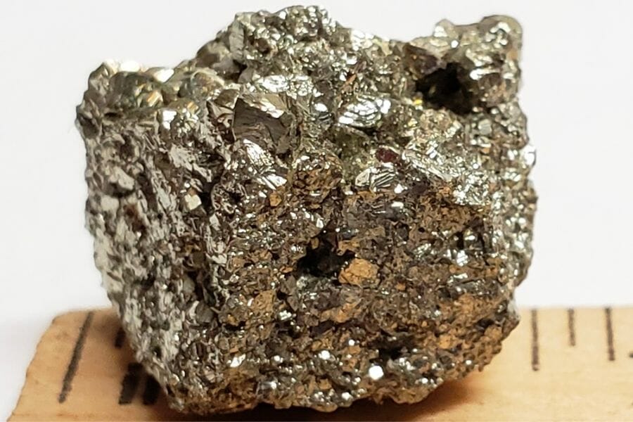 A close up look at a Pyrite Specimen lying on a wooden ruler