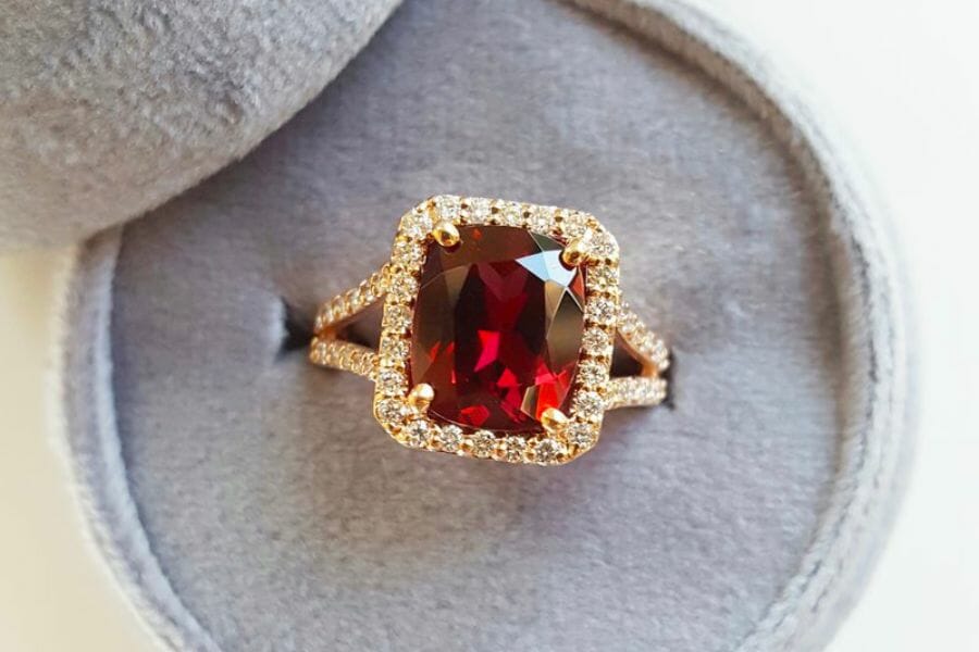 A sparkling cushion-shaped red Rhodolite as a center stone in a golden ring