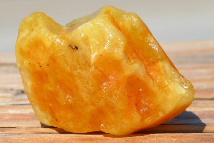 A vibrant yellow amber sitting on a smooth wooden surface