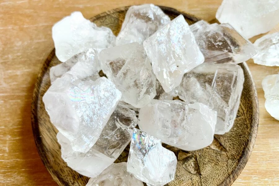 A bunch of clear and white Calcite crystals atop a wooden plate