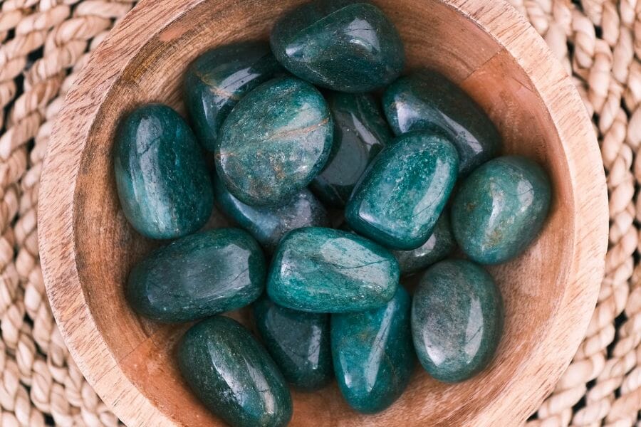 A bunch of polished, deep blue green Fuchsite crystals in a wooden bowl