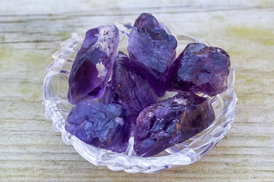 A few pieces of dark purple amethysts inside a glass bowl
