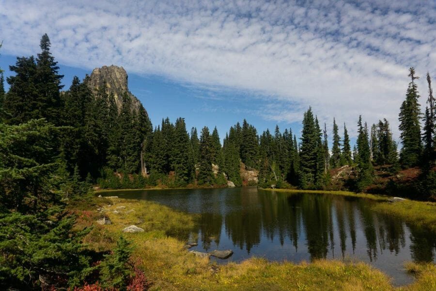 A scenic view of the Cathedral Peak with a lake in the middle surrounded by trees