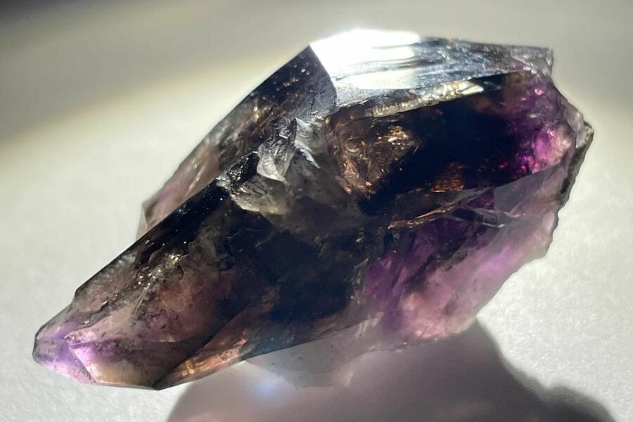 A dark amethyst crystal with a smooth surface and irregular shape 
