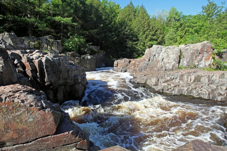 A rushing Eau Claire River in between big rocks