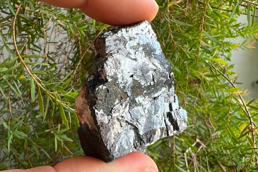 A lustrous, silver Galena specimen held by two fingers