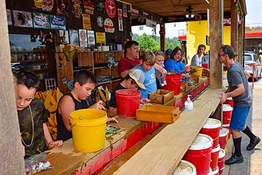 Children and their parents sifting through dirt at the sluice of Goats of the Roof of the Smoky Mountain