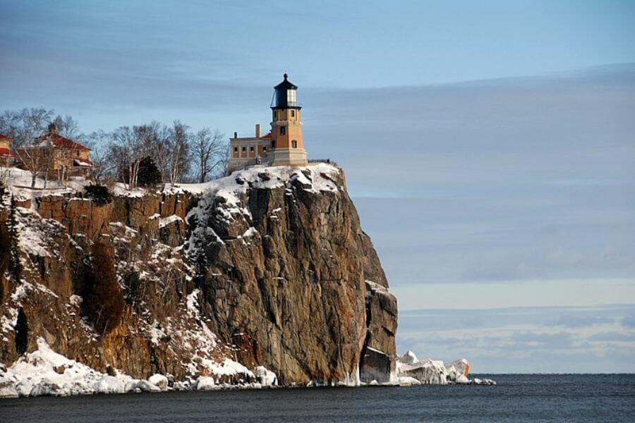 A pretty lighthouse sitting by the edge of a snowy cliff