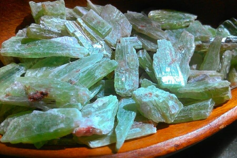 A bunch of green Kyanite crystals on a wooden platter