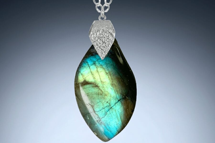 A polished Labradorite with bluish green labradorescence used as pendant on a silver necklace