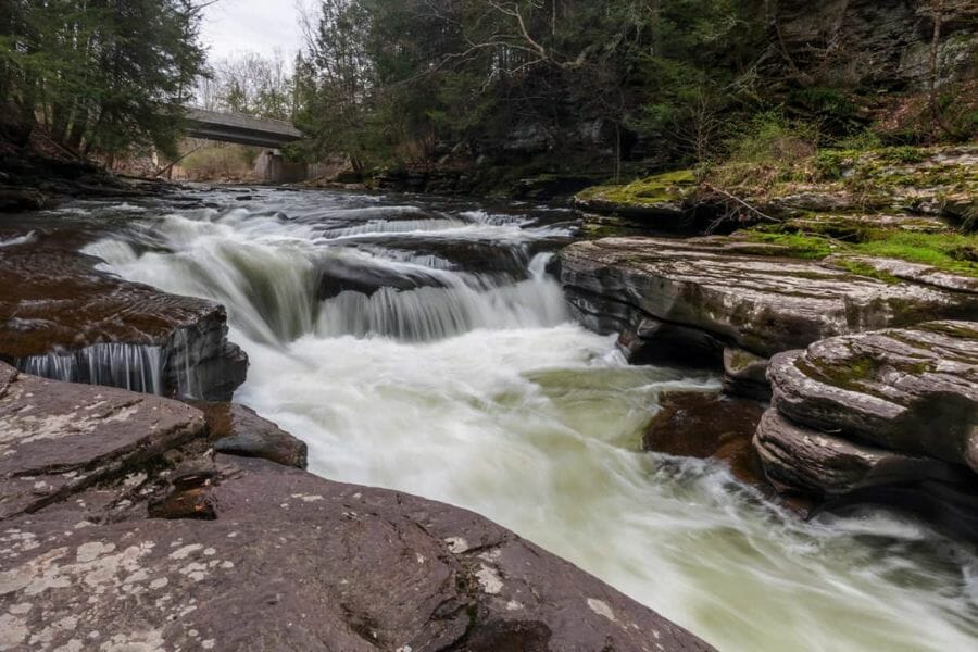 A rushing river surrounded by big rock beds where minerals are being flushed down the area