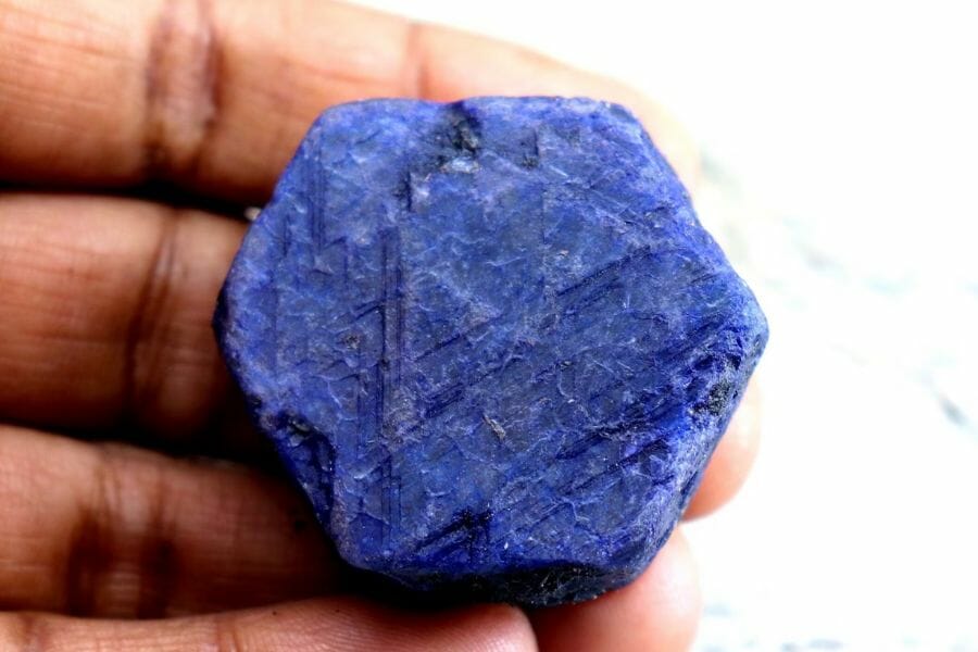 A gorgeous hexagon-shaped sapphire crystal sitting on a hand