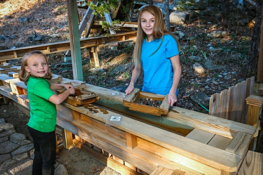 Two children smiling and posing while sifting for gems at the Talking Rocks Cavern