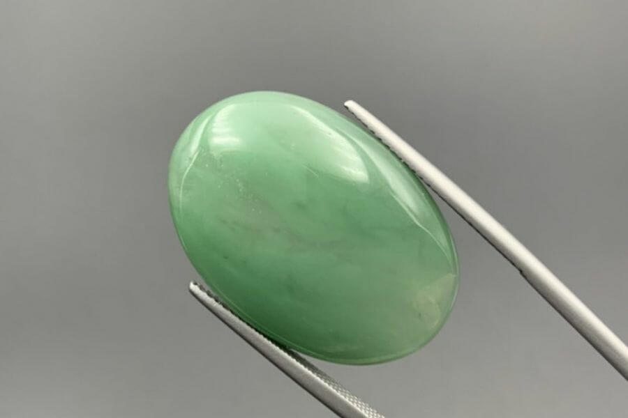 An aventurine cabochon being appraised for its value