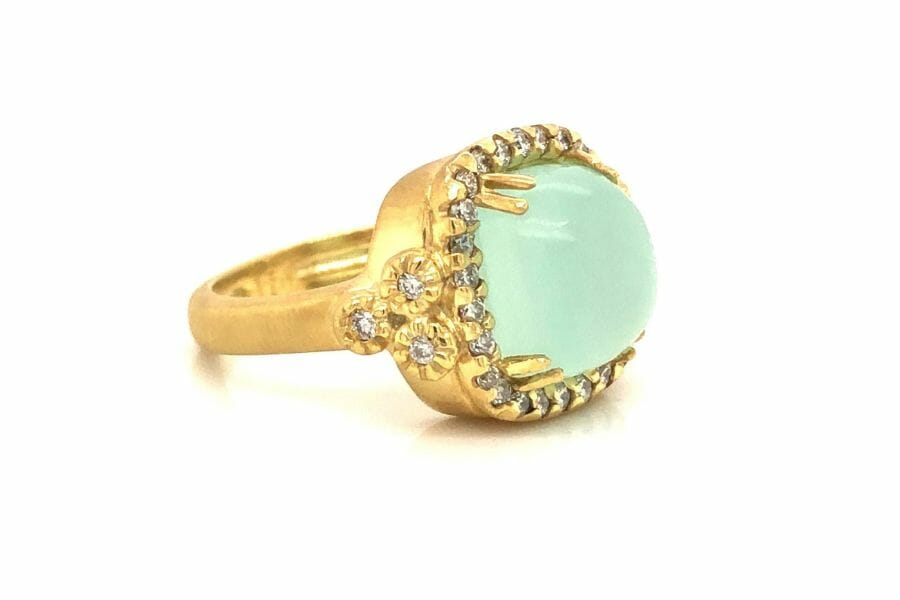 A gorgeous green chalcedony gemstone with diamond crystals and flower details on a gold ring 