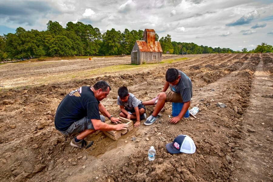 A man and 2 young boys searching for Diamonds at the search area of Crater of Diamonds State Park