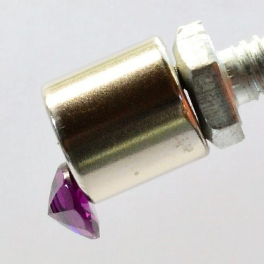 A magnet attracting a polished, purple specimen