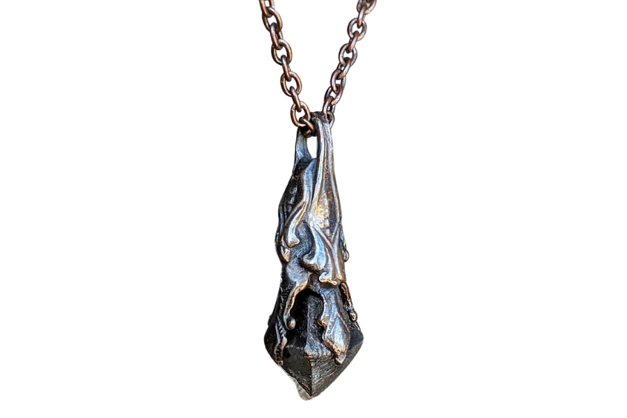 A beautiful, intricately-designed raw, black Magnetite on a bronze pendant