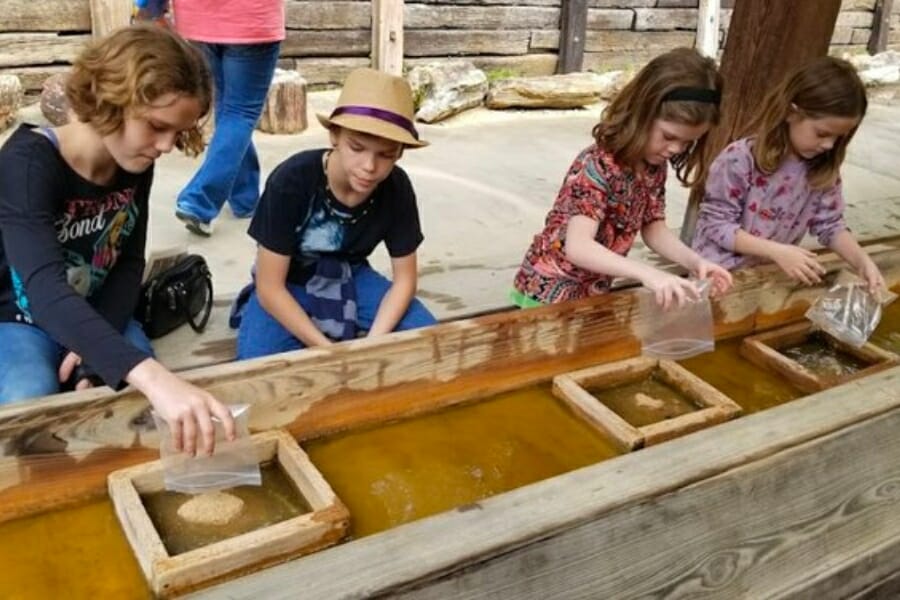 Children sifting through dirt for gems at the sluice of the Mississippi Petrified Forest