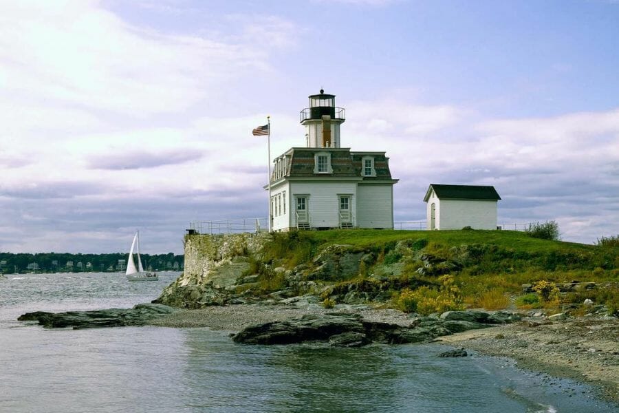 A lighthouse standing at the cliff at Narragansett Bay and its rocky shores