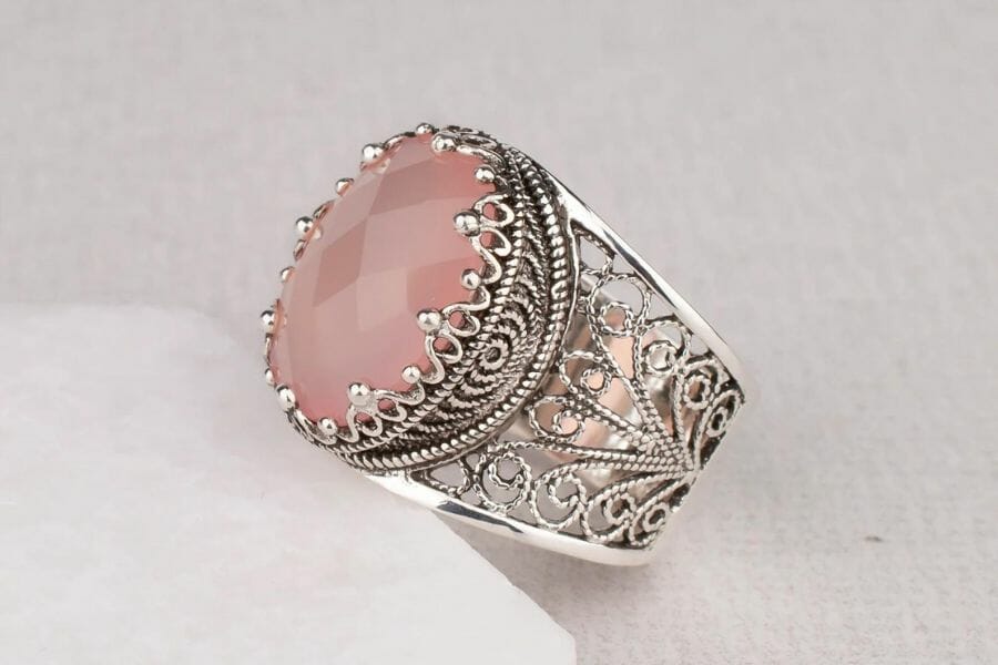 An elegant pink chalcedony silver ring with intricate details and patterns