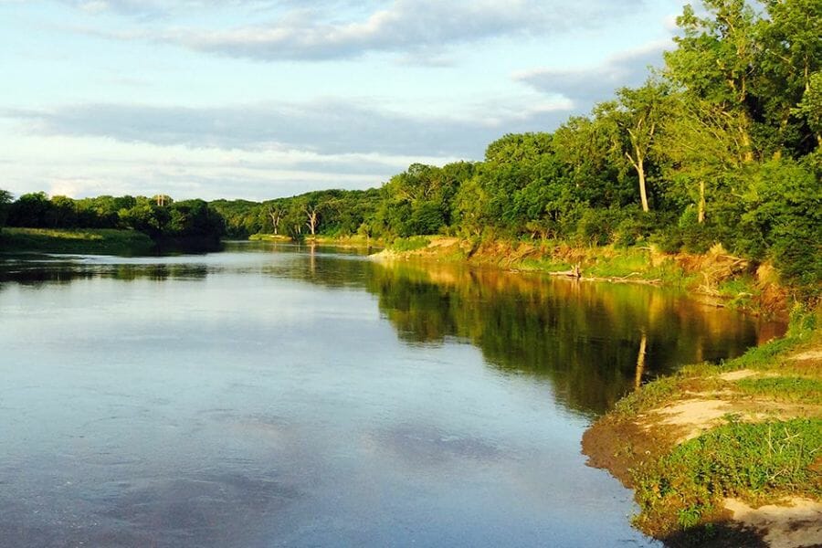 A picturesque view of the Raccoon River surrounded by lush green trees