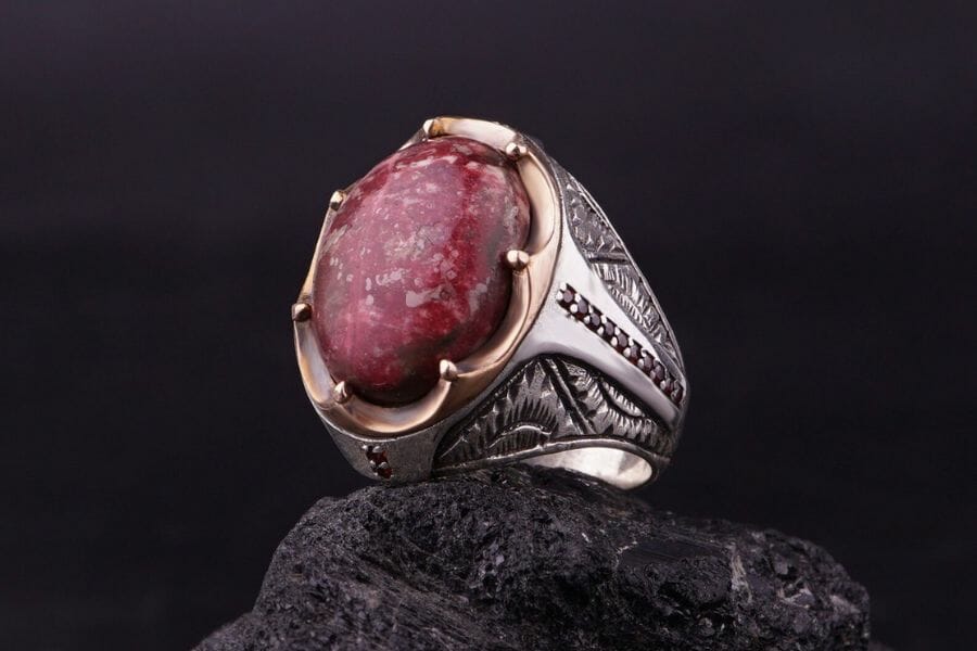 A mesmerizing red aventurine ring with beautiful patterns and is sitting on top of a rock