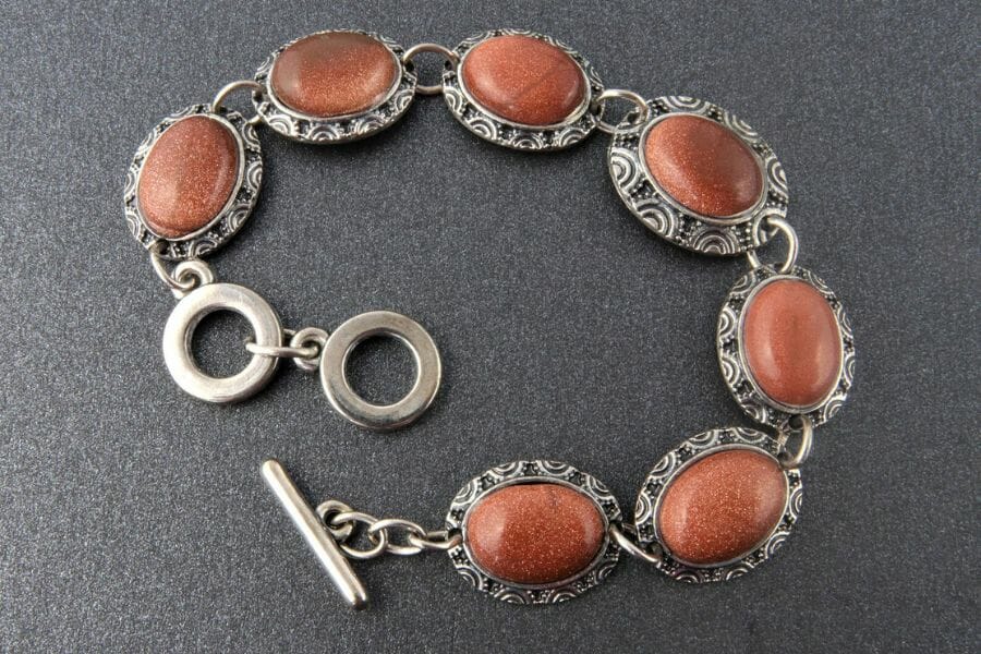 Six pieces of oval cut sandstone on a bracelet with intricate details around them