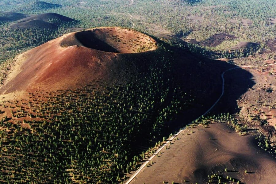 A historic Sunset Crater surrounded by trees and sand 