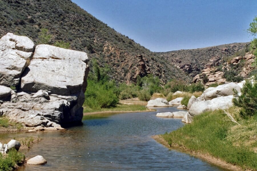 Calm and serene Agua Fria River by the mountain side with a huge rock formation along the riverbank