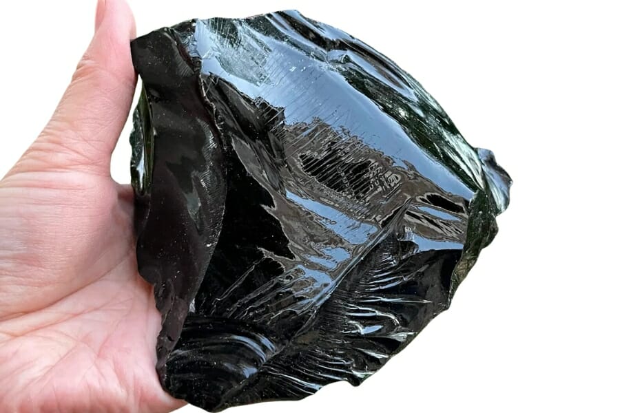 Glassy, shiny black Obsidian held by a hand