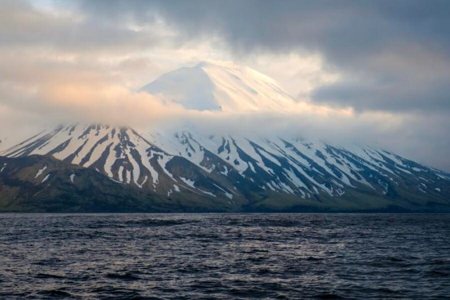 Wide view of snow-capped Tanaga Island foregrounded by vast waters