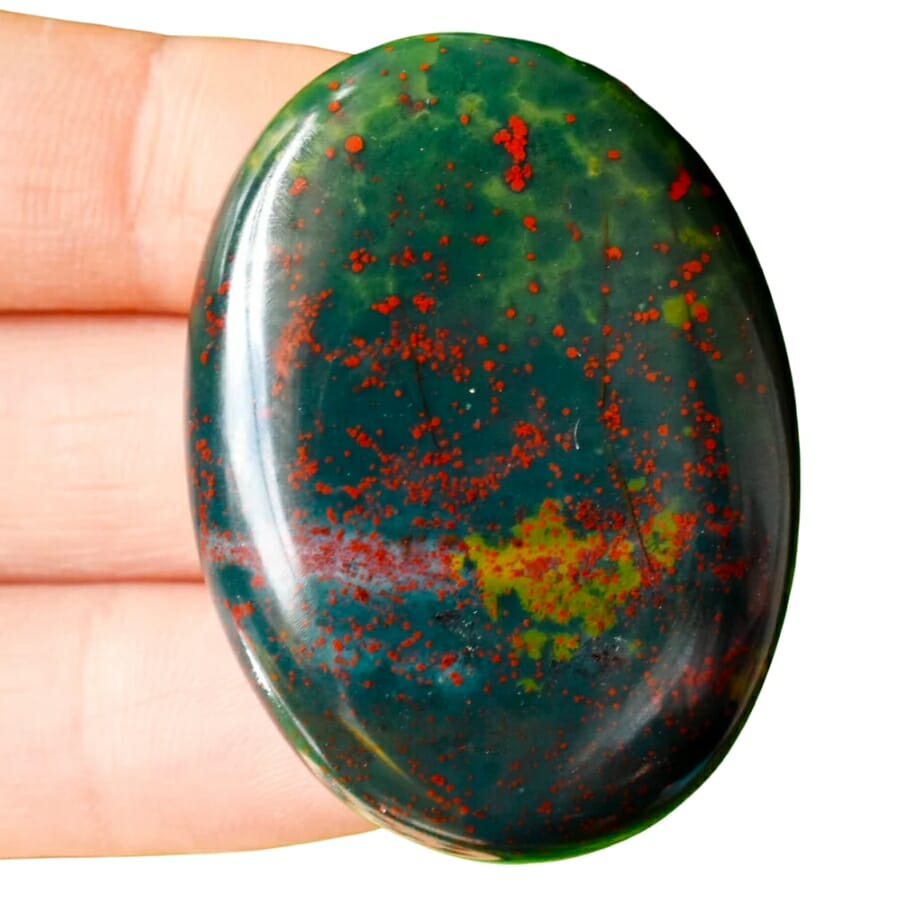 An opal-shaped polished bloodstone held out on three fingers
