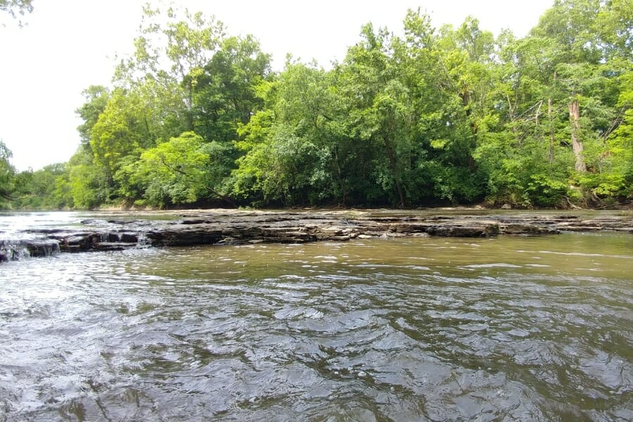 Rushing waters of Big Blue River surrounded by lush green trees