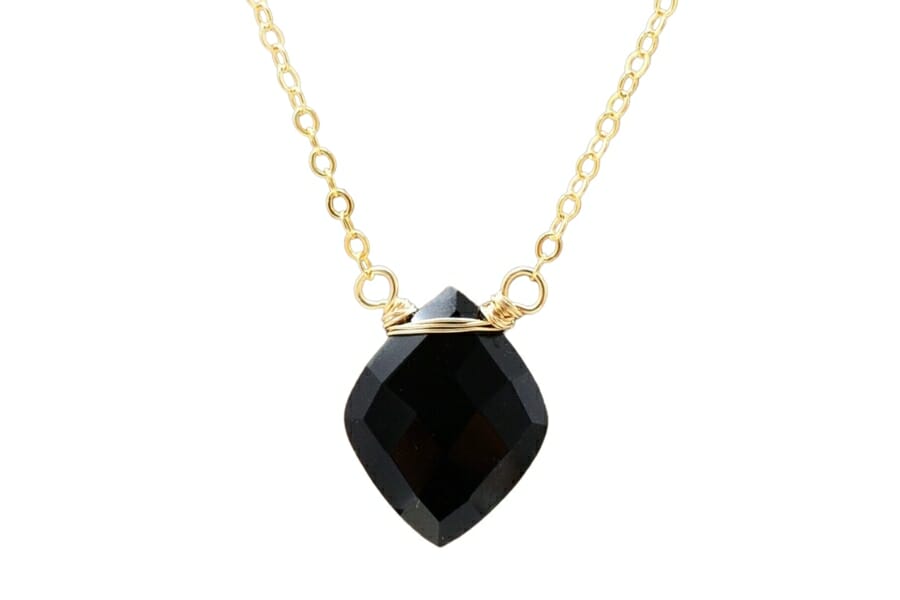 A diamond-shaped onyx pendant with a gold chain