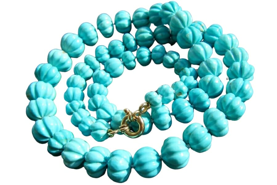 A unique carved out turquoise heirloom necklace with a bright blue hue