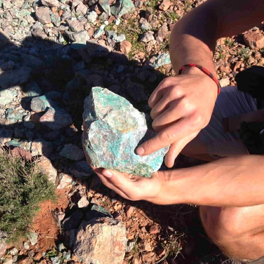 A hand pointing to the different colors in a rock