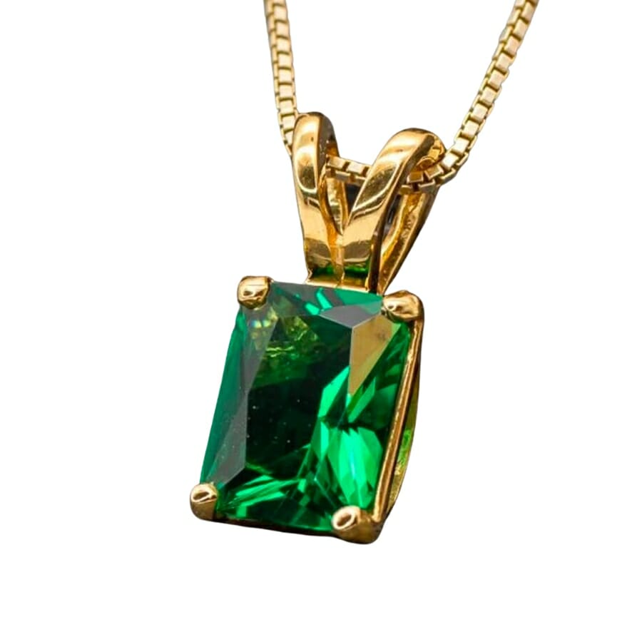 Stunning piece of lustrous green emerald set as a gold pendant's center stone