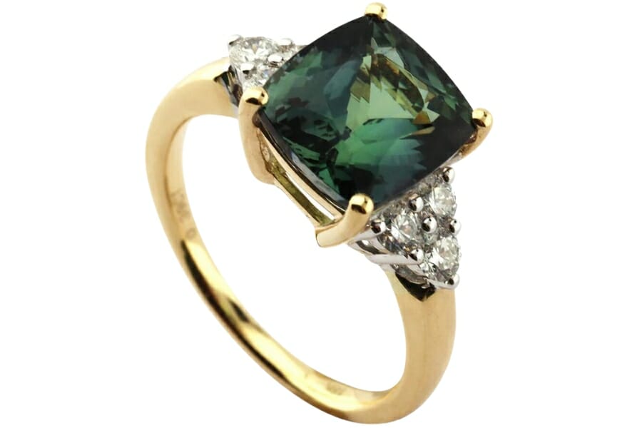 A gorgeous green tanzanite gold ring with diamond stones on each of its side