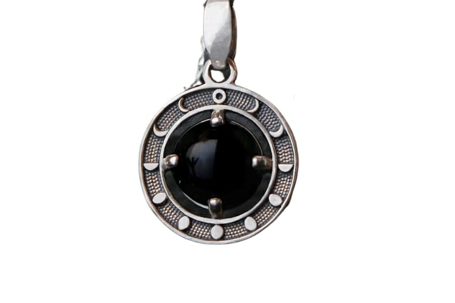 A unique black obsidian pendant with a design that features the phases of the moon