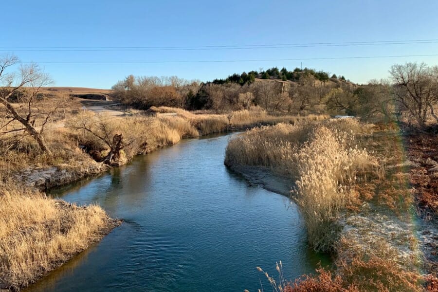 A calm and serene blue water river flowing through scenic grasslands