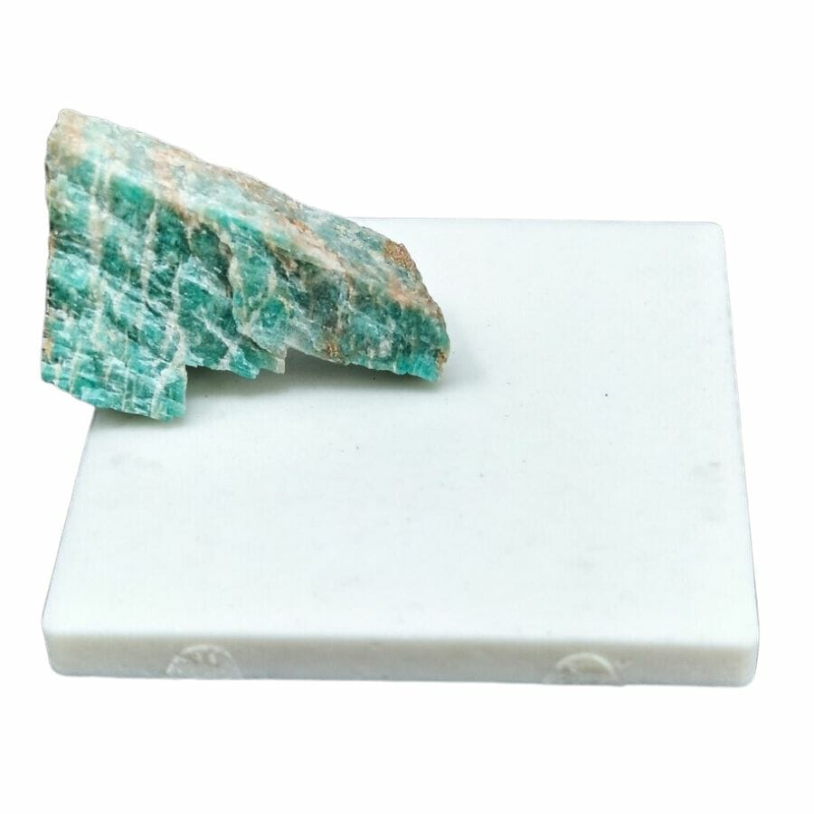 white ceramic streak plate with a rough piece of green rock
