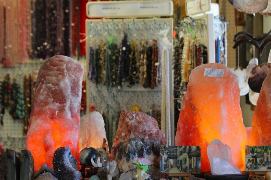 store shelf displaying lamps, minerals, and crystals, with necklaces in the background