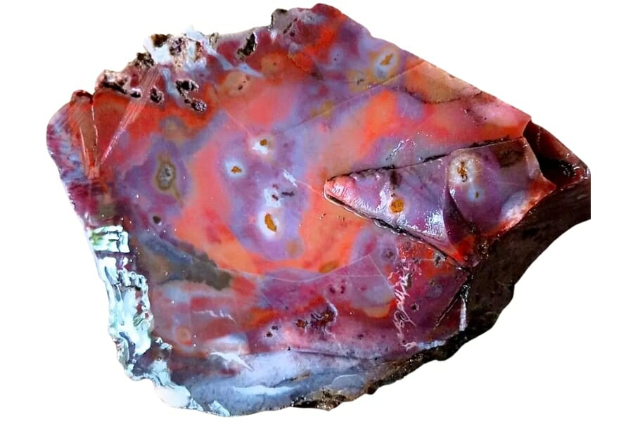 A slab of cut agate with a mix of violet, red, and orange hues