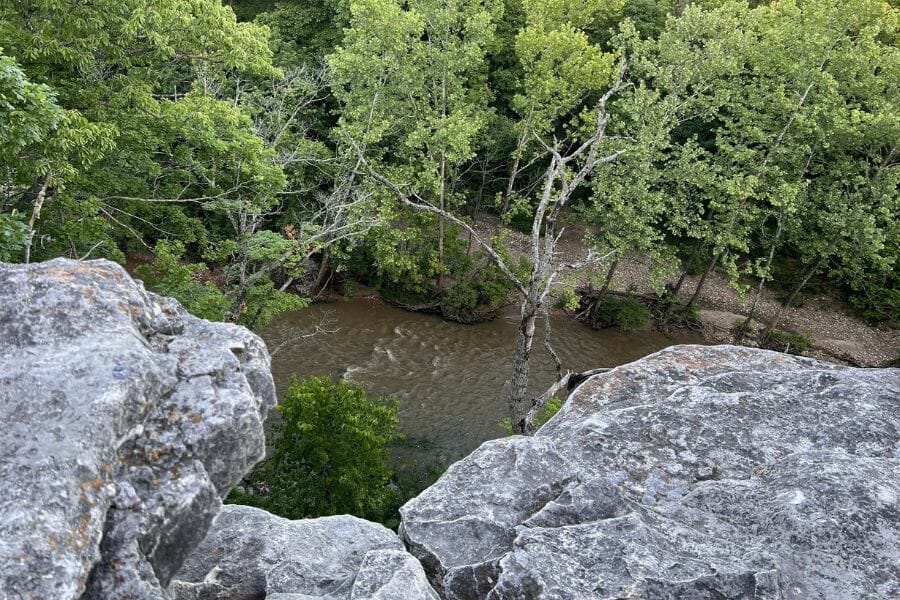 view of a creek and trees from a rocky cliff
