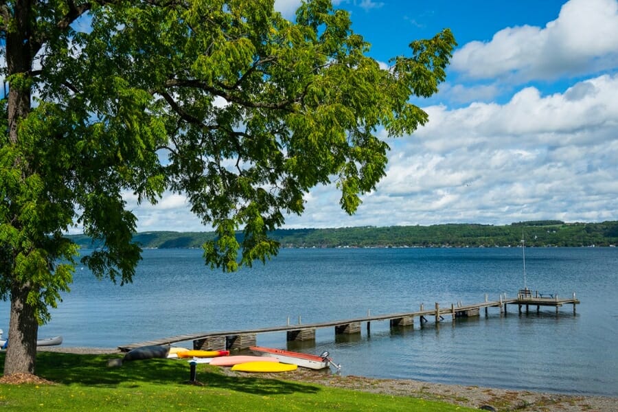 Peaceful waters of Cayuga Lake where kayaks are parked under a tree