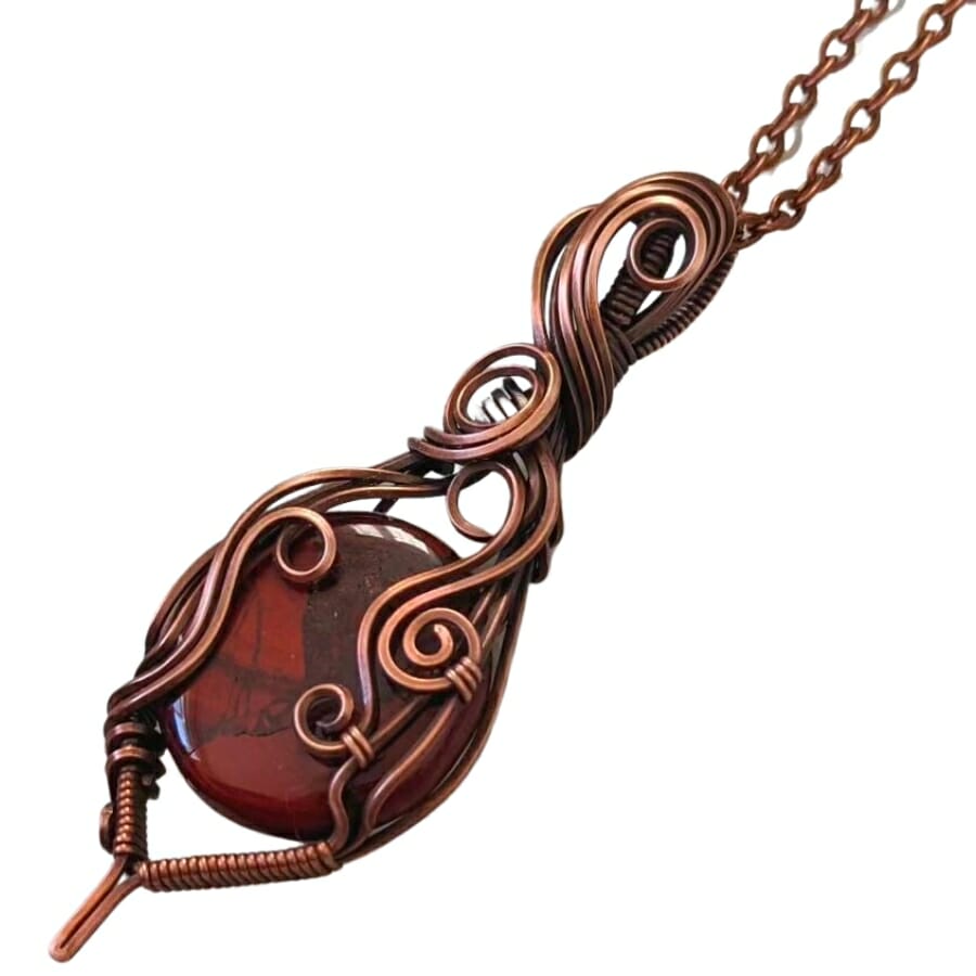 A red jasper cabochon set as center stone in a swirly cage wrap pendant