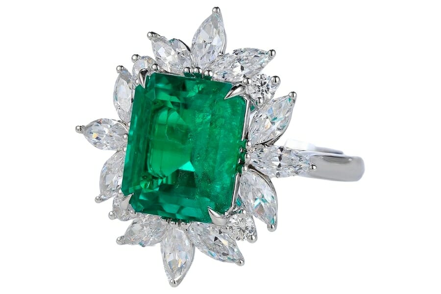 A silver ring with petal-shaped white crystals and a rectangular green emerald