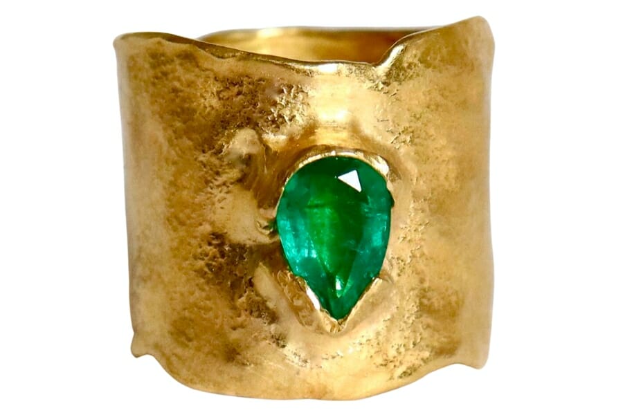A thick golden band with a pear-shaped yellow green emerald