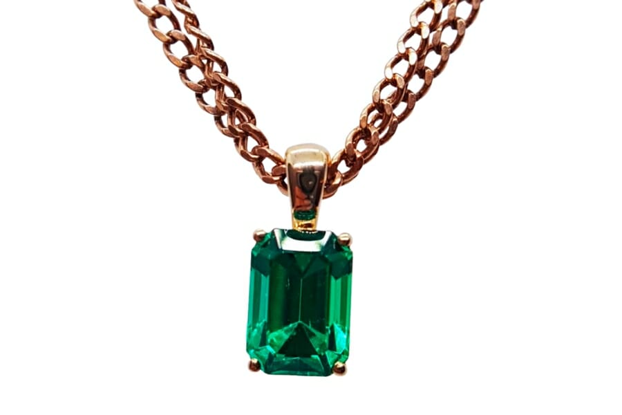 A stunning, vivid green emerald set on a gold pendant